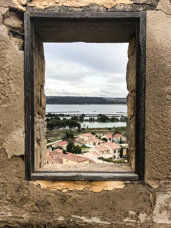 Durch eine Maueröffnung an der Église Saint Saveur eröffnet sich der Blick auf den Étang de l'Estomac