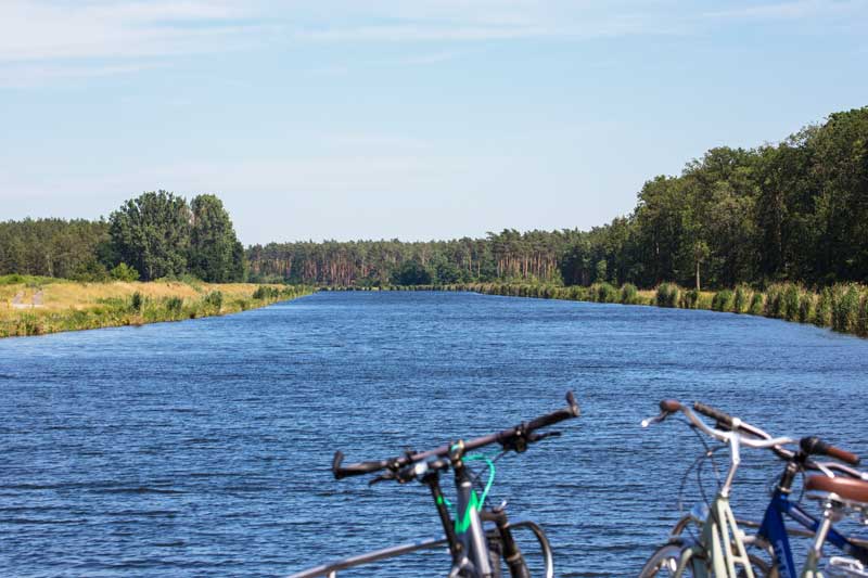 Der Elbe-Havel-Kanal erstreckt sich vor dem Bug in tiefem Blau, zu beiden Seiten Wiesen und Kiefernwälder