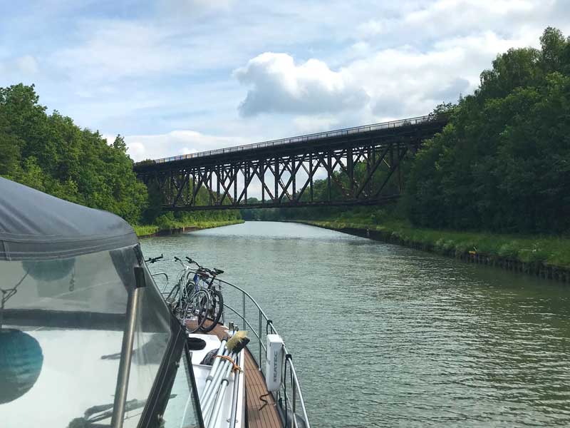 An einer Stelle hinter Braunschweig wird der Mittellandkanal von einer riesigen rostigen Brücke überspannt, die äußerst baufällig aussieht