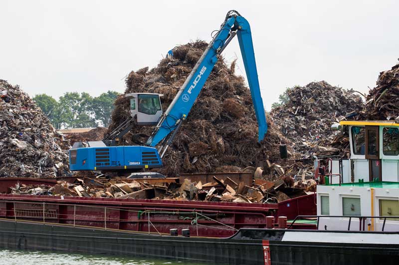 Sortier- und Verladestation für Metallschrott am Mittellandkanal; ein Bagger belädt ein Frachtschiff