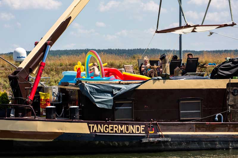 Auf einem Frachtschiff auf dem Mittellandkanal macht sich die Familie einen gemütlichen Sonntag mit Planschbecken für das Kleinkind und Sonnensegel am Autokran