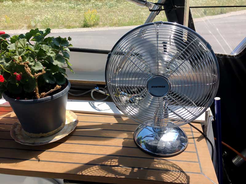 Da es sich unter der Persenning in der Sonne stark aufheizt, bin ich froh um meinen Ventilator, der neben mir steht und für Durchzug sorgt
