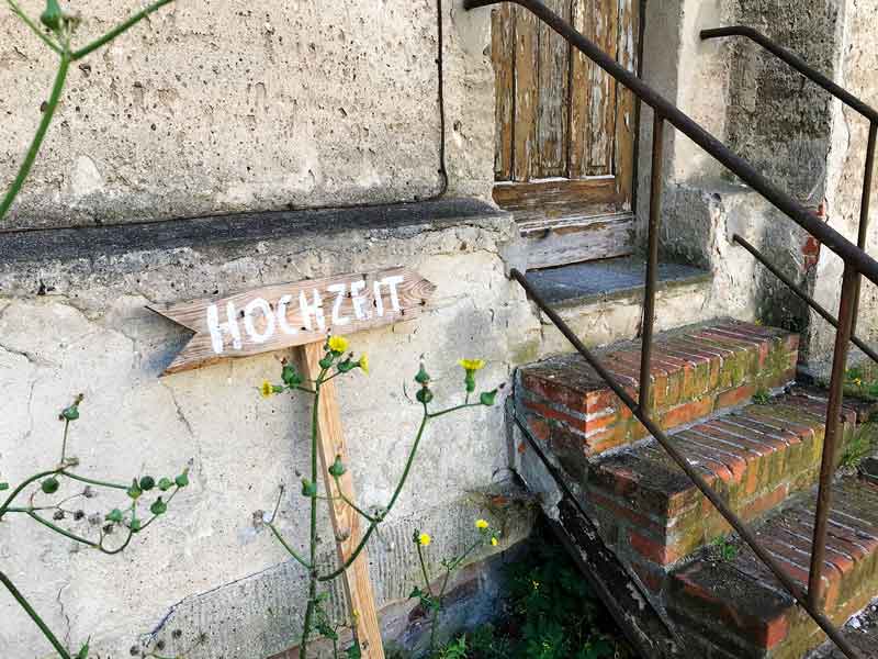 Ein Schild Hochzeit steht vor einer Treppe und alter Holztür im Schloss Plaue am Plauer See in Brandenburg