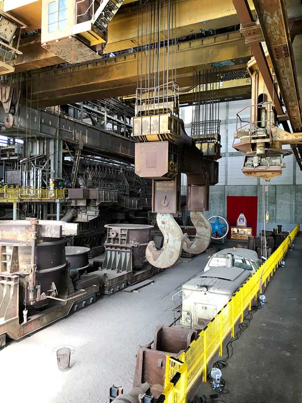 Große Stahlhaken einer Krananlage und eine Werkslokomotive im Industriemuseum Brandenburg an der Havel am Silokanal.