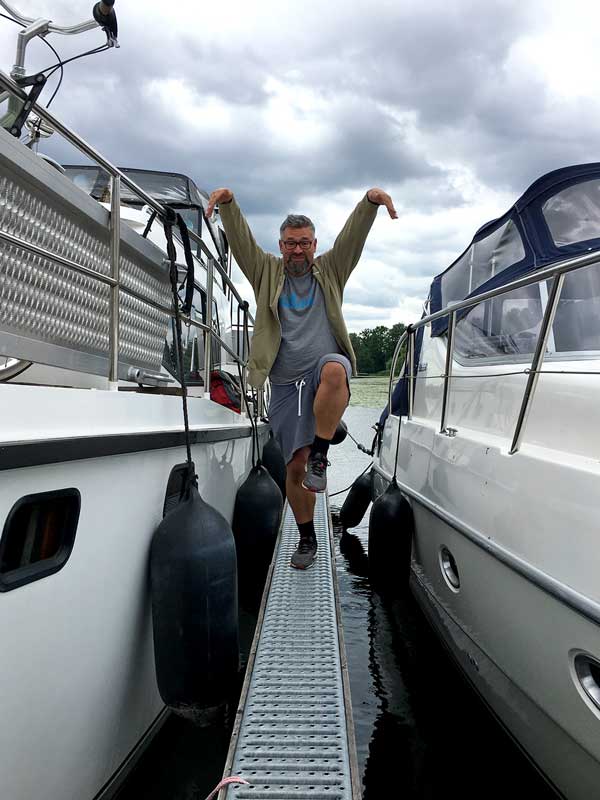 Thomas steht auf einem Bein zwischen zwei Booten auf dem superschmalen Steg des Yachthafens Scheunhornweg in Werder