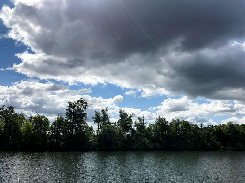 Die Sonnenstrahlen bahnen sich einen Weg durch dunkle Wolken über der Potsdamer Havel zwischen Ketzin und Werder