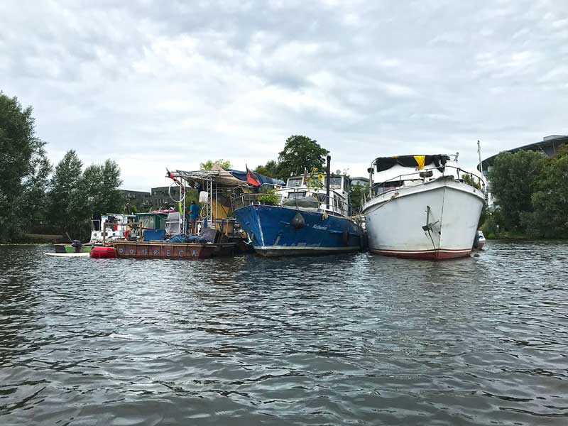 Mehrere Boote und eine Plattform schwimmen auf dem Wasser in der Rummelsburger Bucht auf der Spree in Berlin