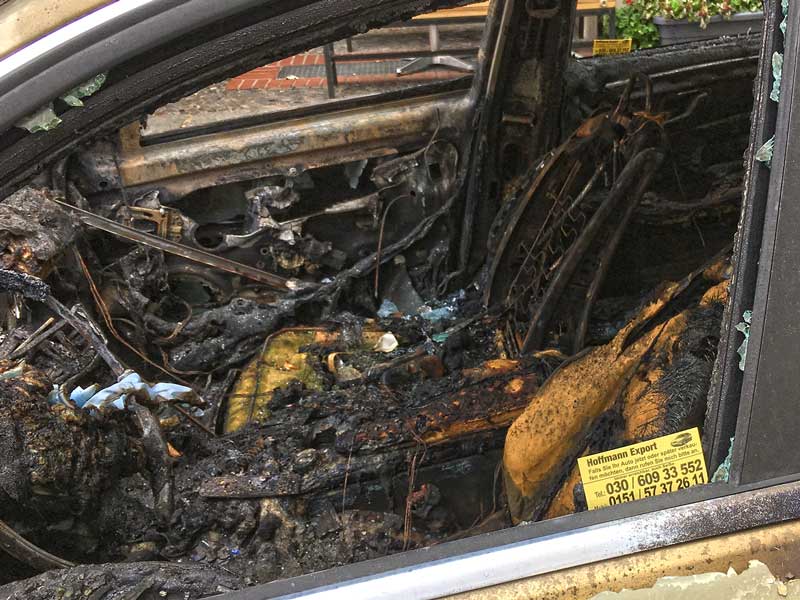 Im Fensterrahmen eines ausgebrannten Autos in im Bergmann Kiez in Berlin Kreuzberg steckt die Karte eines Händlers, der Fahrzeuge für den Export ankauft