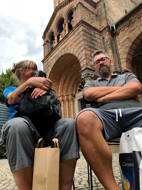 Die Eltern sitzen auf neuen Stühlen vor der Sankt Peter und Paul Kirche am Bassinplatz in Potsdam