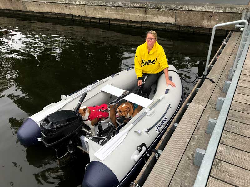 Barbara, die zwei englischen Bulldoggen und der schwarze Mops sitzen in einem Schlauchboot am Steg vor dem Schloss von Köpenick bei Berlin