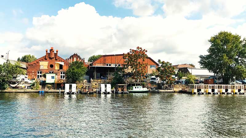 Uferbebauung mit alten Häusern aus Sichtziegel und Hausbootverleih am Ufer der Spree bei Berlin