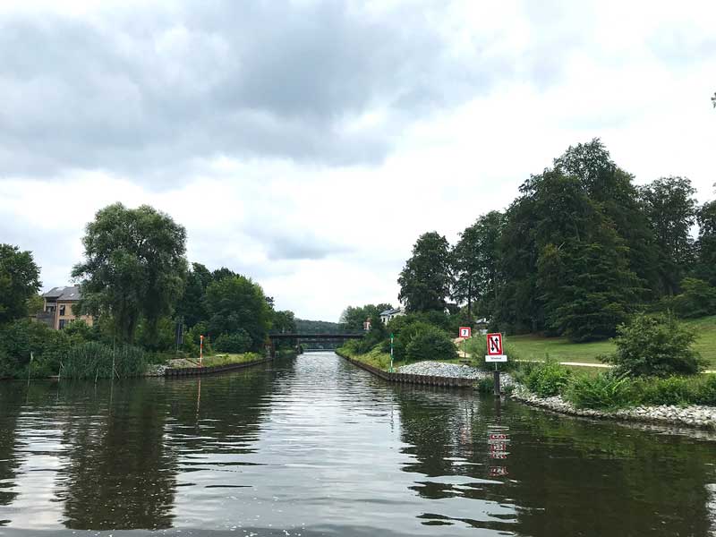 Die Durchfahrt vom Tiefen See in den Griebnitzsee ist sehr schmal und führt unter einer Brücke durch. Rechterhand reicht der Park Babelsberg Potsdam bis ans Ufer