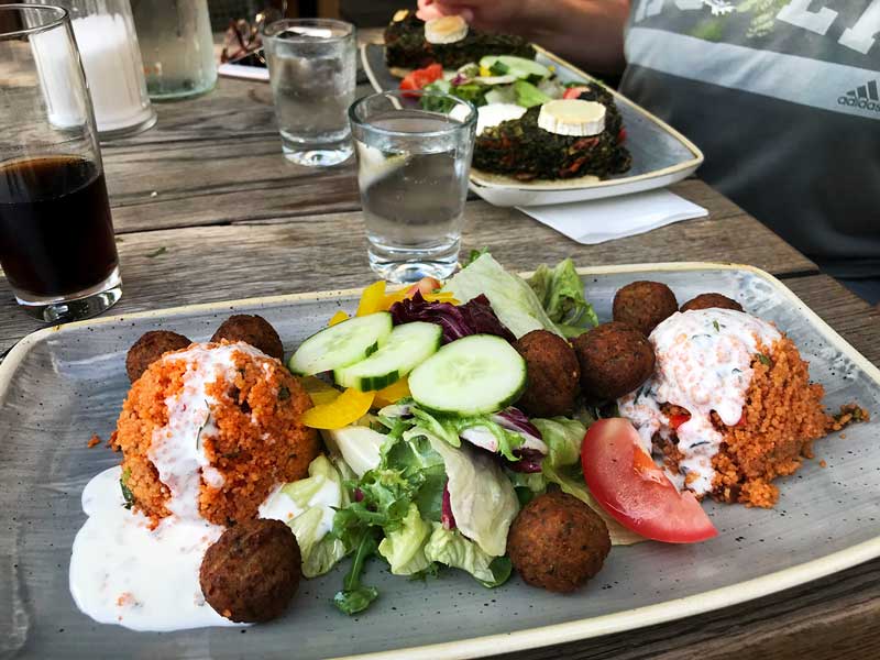 Ein Teller mit einem vegetarischen Gericht aus Quinoa, Falafel und Salat auf einem Tisch im Restaurant Hafenküche in der City Marina Rummelsburg auf der Spree in Berlin