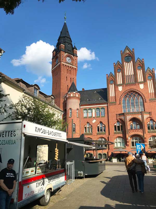 Verkaufsstände auf dem Stadtfest in Köpenick bieten Koblauchbaguette und Softeis an - im Hintergrund das Rathaus