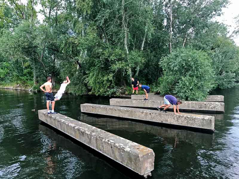Parkour Sportler der Gruppe Ashiguru Parcour & Freerunning um Benni Grams trainieren auf Betonklötzen im Wasser hinter der City Marina Berlin Rummelsburg an der Spree