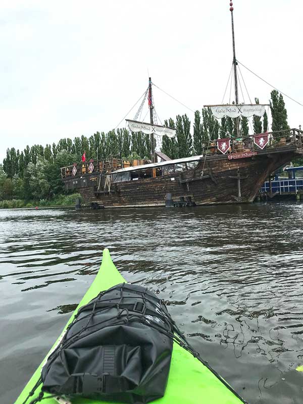 Das Kajak fährt auf ein altes Zwei-Mast-Segelschiff aus Holz zu in der Rummelsburger Bucht auf der Spree in Berlin, das Restaurant Schiff Gode Wind, Requisite aus dem ARD Zweiteiler Störtebeker