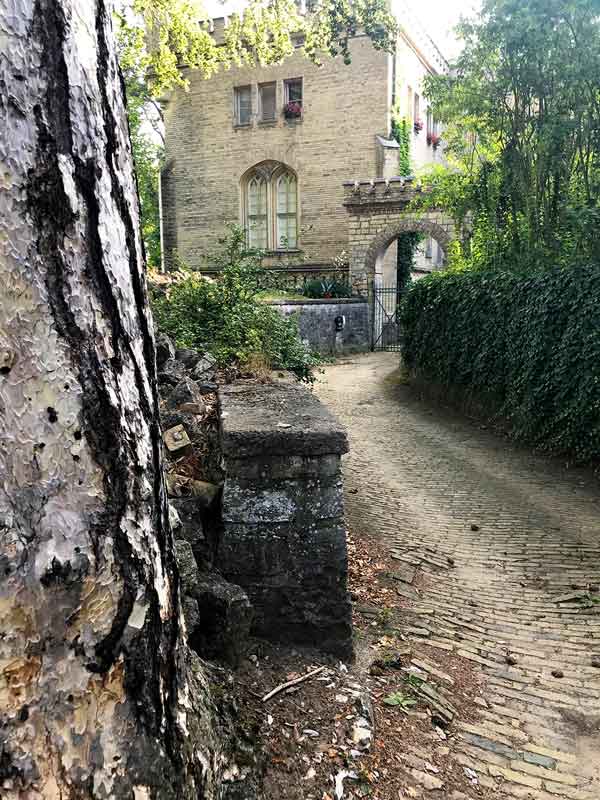 Kleiner Weg mit Kopfsteinpflaster führt zu einem historischen Bauwerk, die ehemalige Schlossküche des Schlosses Babelsberg in Potsdam