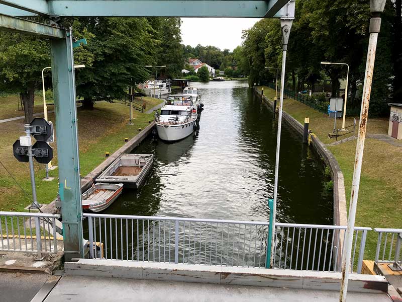 Blick von der Brücke über die Dahme-Wasserstraße auf die Zugbrücke und mehrere Sportboote, die auf die Schleusung in der Schleuse Neue Mühle in Königs Wusterhausen, Brandenburg, südlich von Berlin warten.