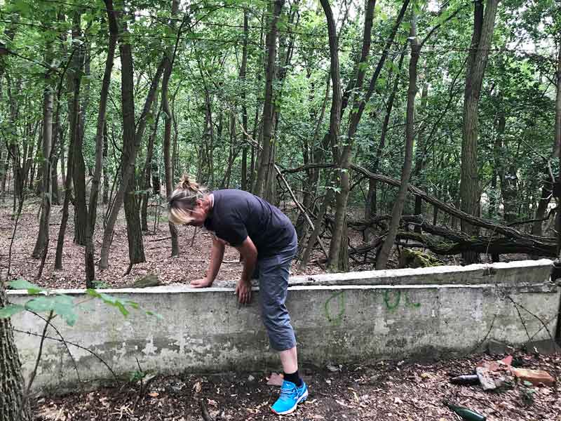 Frau klettert über zusammengebrochene Betonmauer im Wald