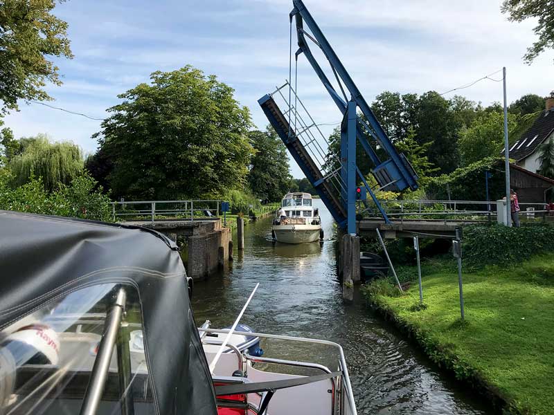 Blick zurück auf die geöffnete Zugbrücke über den Kanalgraben in den Teupitzer Gewässern, Brandenburg, Dahme-Wasserstraße südlich von Berlin. Man sieht, dass die Durchfahrtshöhe und -breite auch bei geöffneter Brücke eingeschränkt sind aufgrund des Hebewinkels