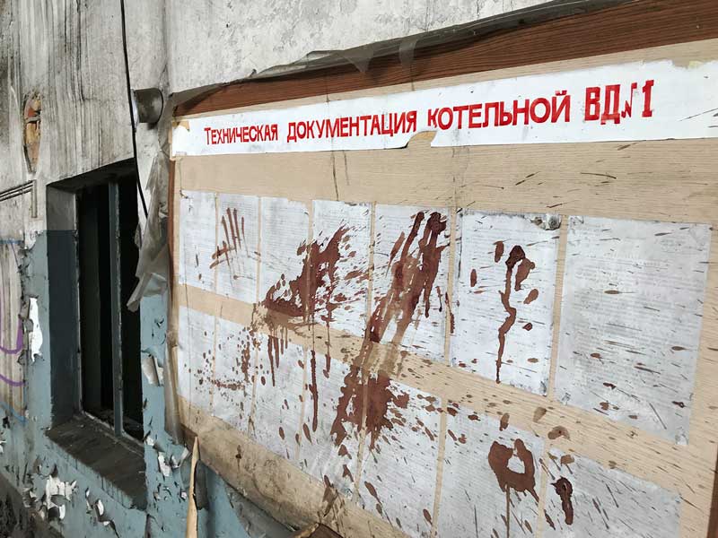 Ein Anschlagbrett mit Aushängen in russischer Sprache ist mit Spitzern überzogen, die wie getrocknetes Blut aussehen. Landesirrenanstalt Teupitz, Brandenburg, südlich von Berlin - Lost Places