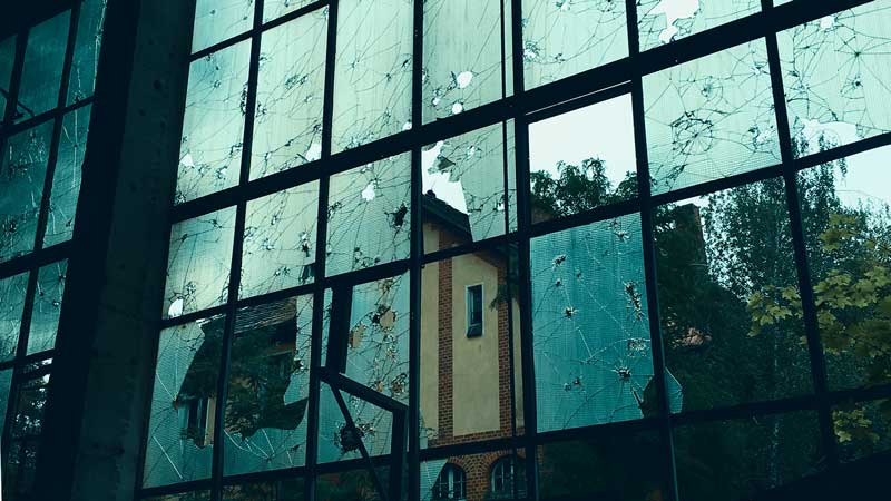 Blick durch zerlöcherte Scheiben auf zerfallene Gebäude