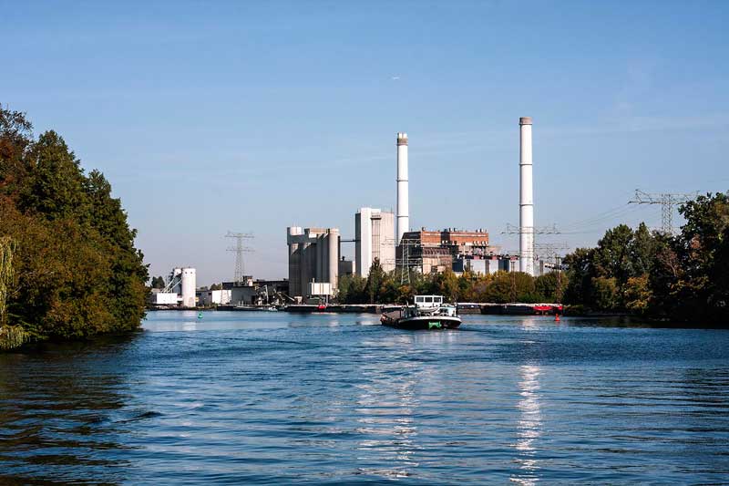 Am Ufer der Spree bei Berlin Rummelsburg ragen große Schornsteine und Indsutriebauten in die Luft, die zu einem Heizkraftwerk sowie einem Zementwerk gehören