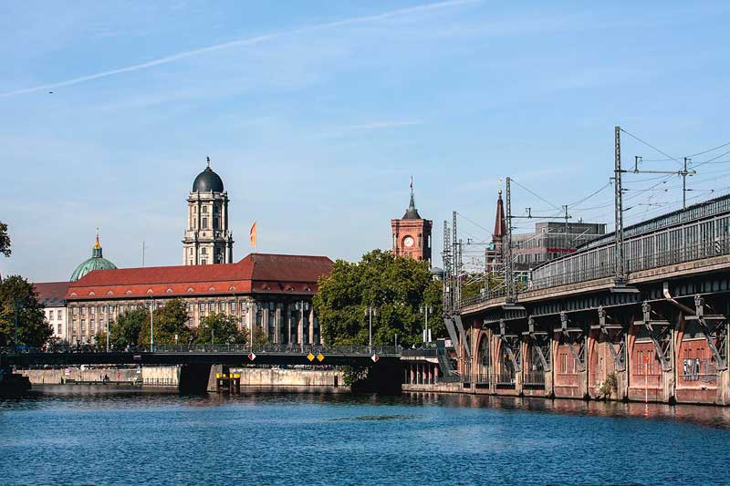 Am Ufer der Spree in Berlin verläuft rechterhand das alte, aus Ziegeln gemauerte Hochgleis der U-Bahn. Vor uns die Jannowitzbrücke über die Spree