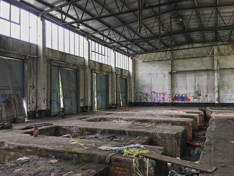 In dieser ehemaligen Maschinenhalle der Landesirrenanstalt Teupitz, Brandenburg, südlich von Berlin, hängen die Einfahrtstore schief und verbeult in ihren Aufhängungen. Die Gräben sind mit Müll übersät, die Wände mit Grafitti besprüht - Lost Places
