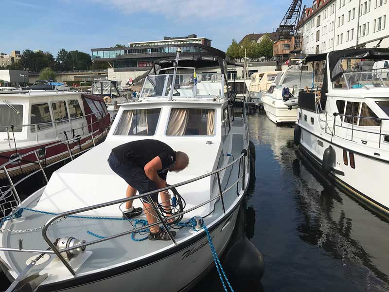 Mann auf einem Charterboot verzieht ein Stromkabel über Deck im Tempelhofer Hafen in Berlin