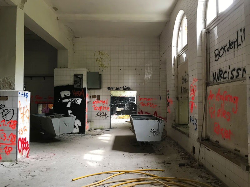 Im ehemaligen Wäschereigebäude der Landesirrenanstalt Teupitz, Brandenburg, südlich von Berlin, sind nur noch ein paar Tröge übrig. Die weißen Fliesen der Halle sind mit Grafitti besprüht - Lost Places