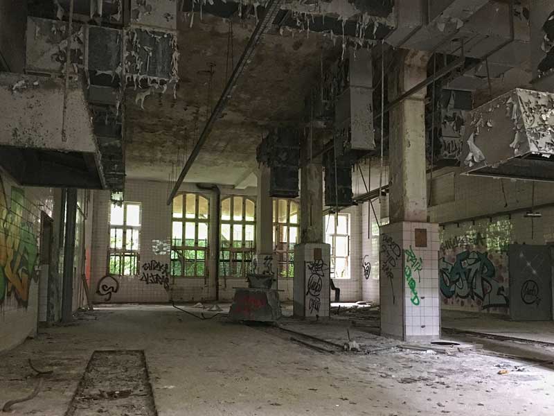In dem sehr hohen und großen Raum der ehemaligen Wäscherei der Landesirrenanstalt Teupitz, Brandenburg, südlich von Berlin, blättert die Farbe von den Entlüstungsanlagen - Lost Places