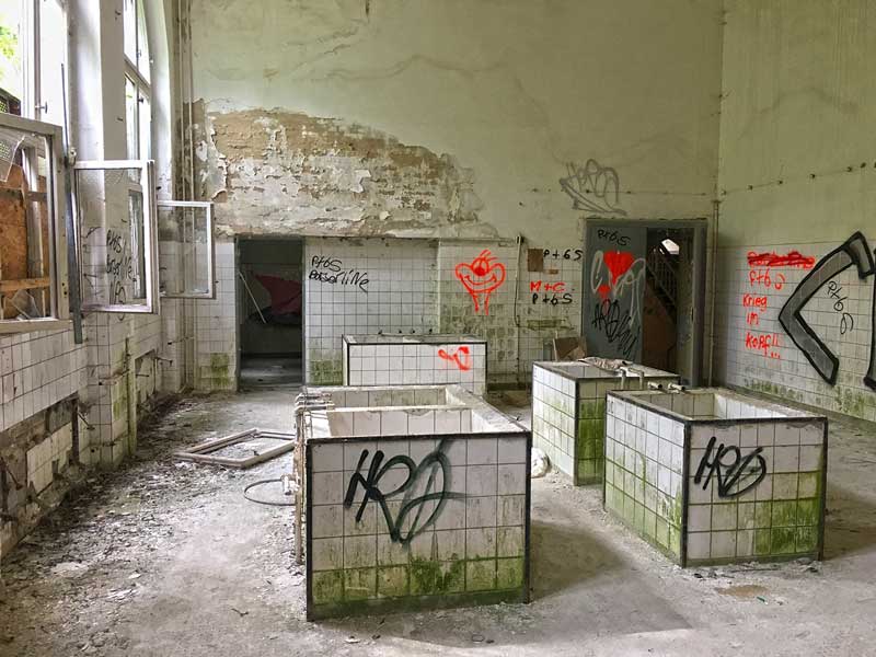 Nur noch weiß gekachelte Tröge sind übrig in diesem Raum der ehemaligen Wäscherei der landesirrenanstalt Teupitz, Brandenburg, südlich von Berlin. Alles setzt schon Moos an und ist mit Grafitte besprüht. Lost Places