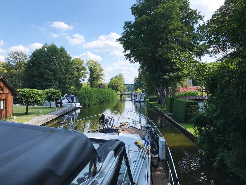 Das Boot wartet in der Kanalmitte auf die Öffnung einer sehr niedrigen Hebebrücke