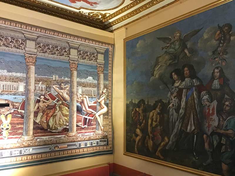 Über Eck hängen hier im Rahmen der Ausstellung B.A.R.O.C.K. im Schloss Caputh, Brandenburg, ein schwülstiges altes Barockgemälde und eine moderne, ironische Tapisserie nebeneinander