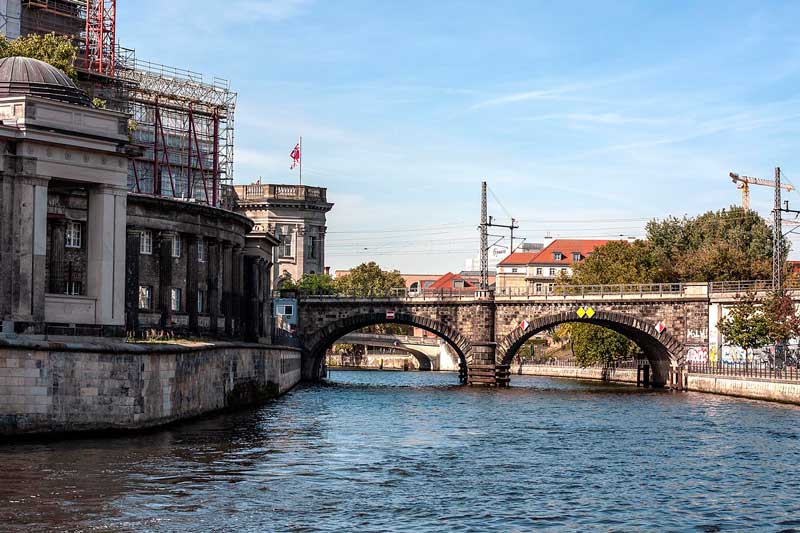 Linkerhand am Ufer der Spree in Berlin die Alte Nationalgalerie auf der Museumsinsel, dahinter zwei geschwungene alte Brücken