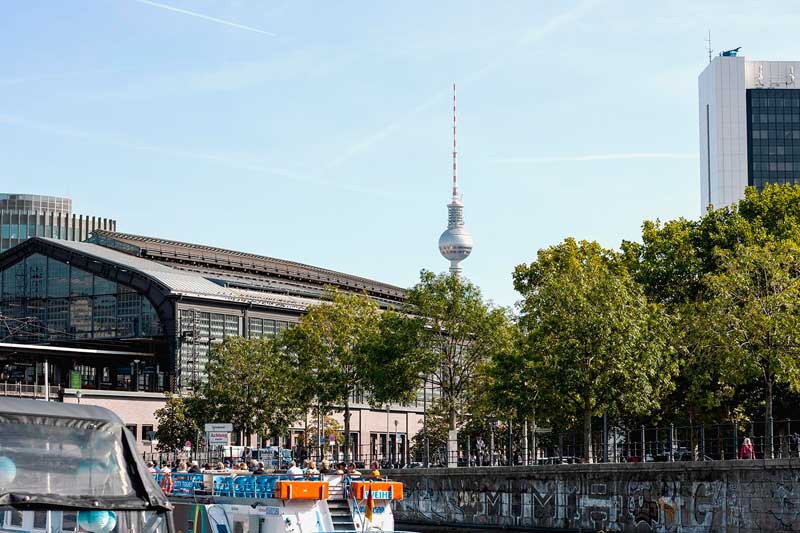 Über dem Bahnhof Friedrichstraße am Ufer der Spree in Berlin erhebt sich der Fernsehturm, der Alex