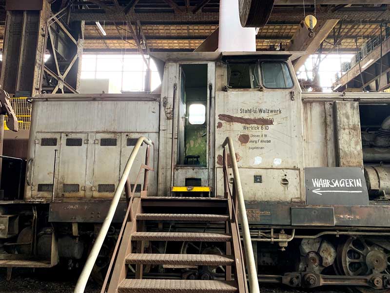 Alte Lokomotive in der riesigen Halle des Industriemuseum Brandenburg an der Havel, an der ein Schild "Wahrsagerin" hängt