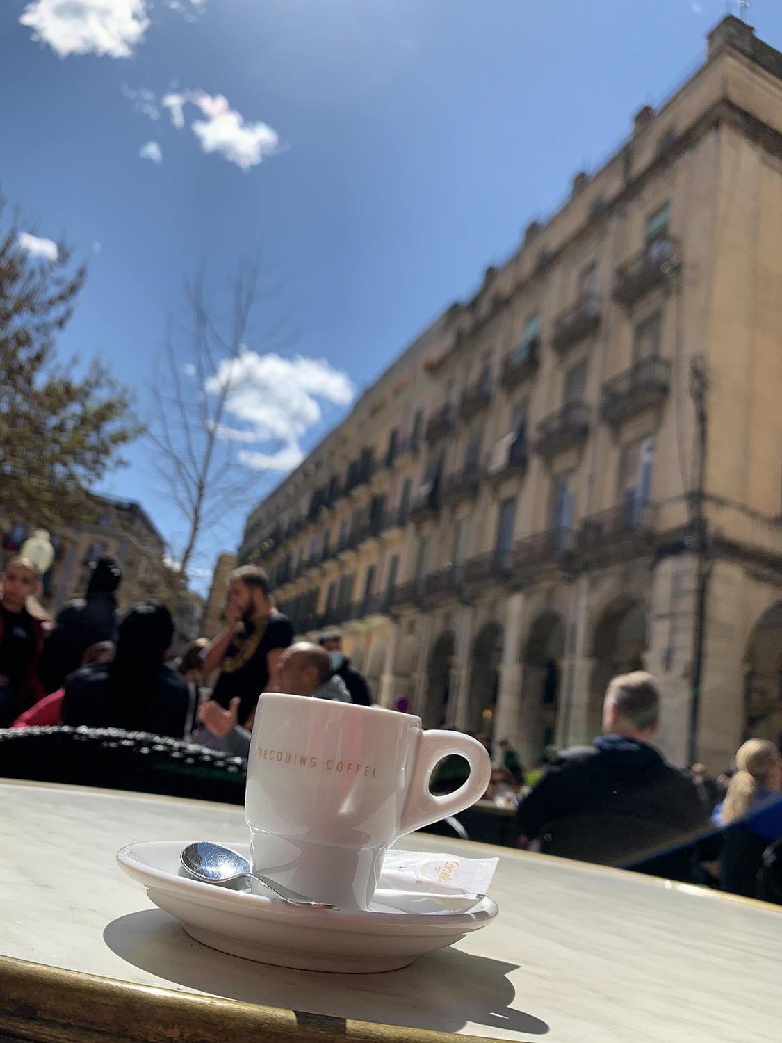 Espresso auf dem Tisch an der Placa Independencia, im Hintergrund Menschen im Café